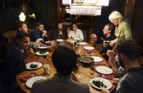 Group of people enjoying a meal together at a round table in a cozy setting.