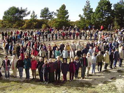 Large group of people gathered outdoors in a circle at Findhorn Foundation.