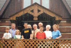 Group of diverse people standing in front of a rustic wooden building.
