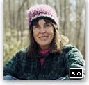 Woman in outdoor setting wearing a pink hat and glasses.