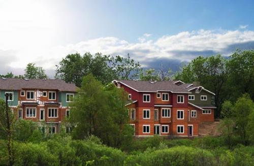 Colorful eco-friendly apartment buildings surrounded by greenery under a blue sky.