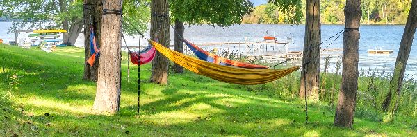Colorful hammocks tied between trees at a lakeside community setting.