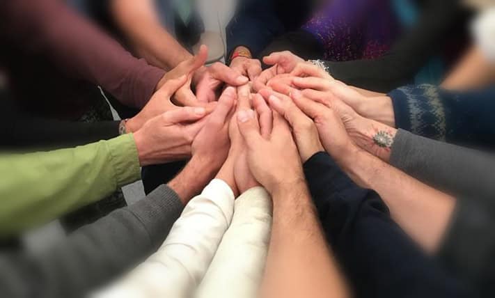Group of diverse hands stacked together symbolizing community and collaboration.