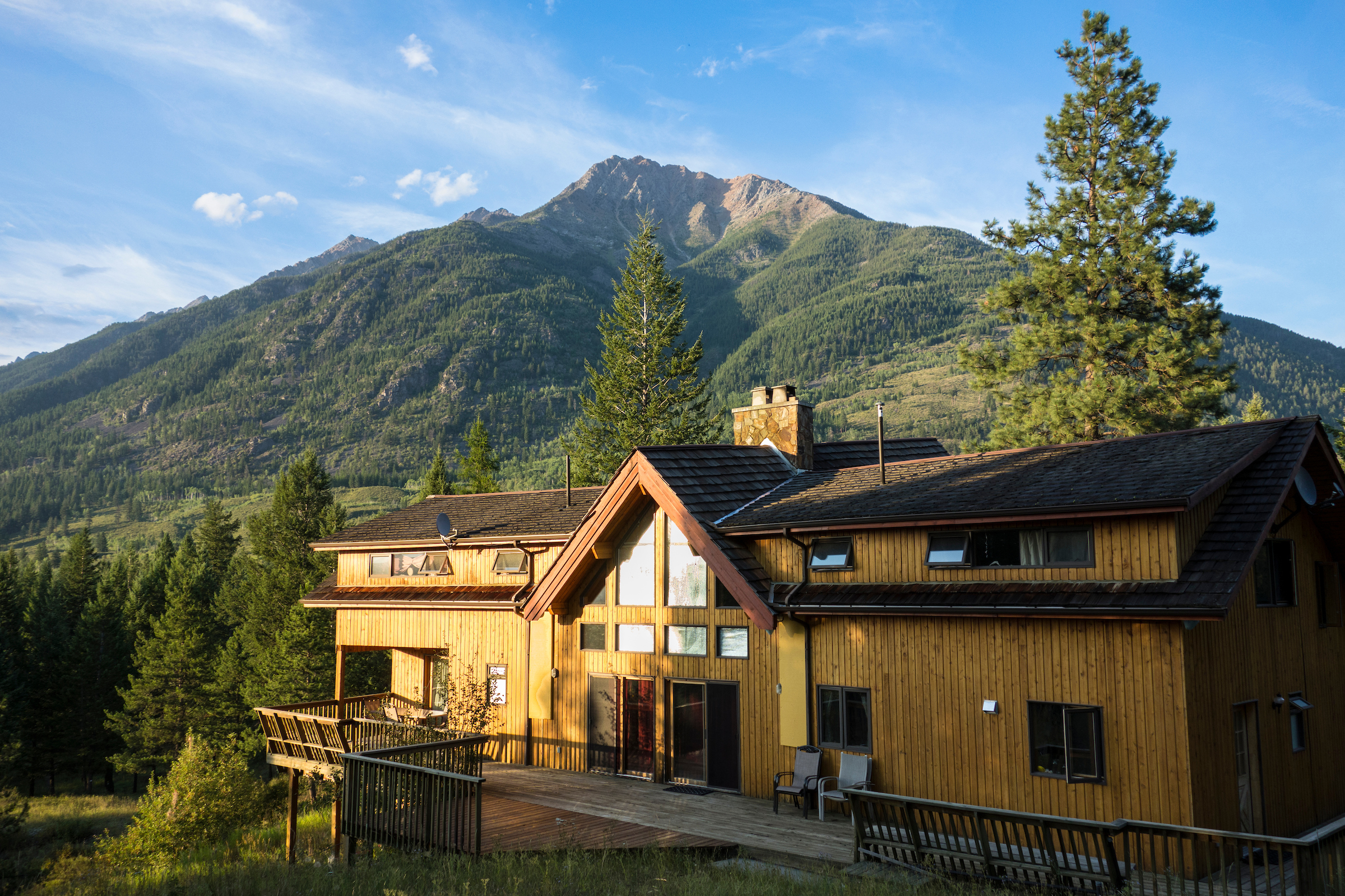 Wooden retreat house with mountain view and lush greenery in the background.