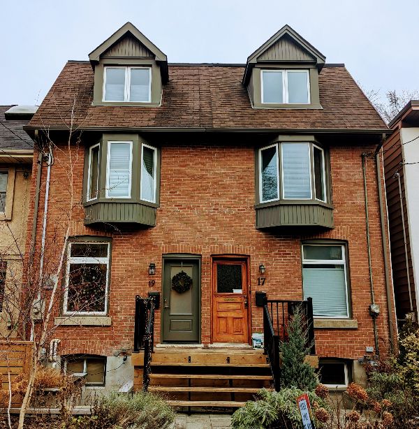 Brick house with green bay windows and dormer windows on roof.