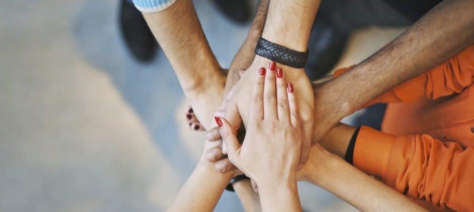Group of diverse people stacking hands in unity for community effort.