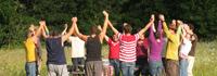 Group of diverse people holding hands in a circle outdoors.