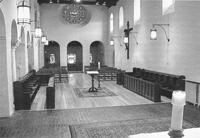 Interior of a historic church with wooden pews and a central altar.