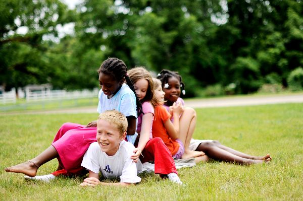 Children playing and laughing outdoors on a grassy field.