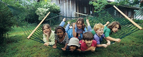 Children playing on a hammock in a community garden setting.