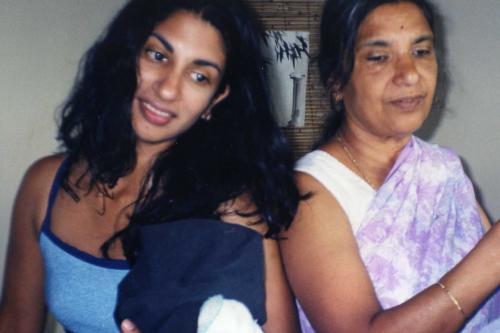Two women smiling, one with long black hair and the other with short hair, in a casual setting.