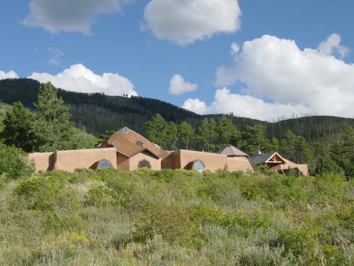 Unique adobe-style community buildings in a lush green landscape under a blue sky.