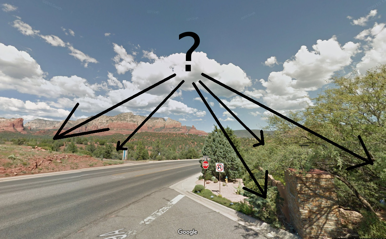 Road with directional arrows pointing to various landmarks in a desert landscape.