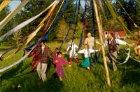Children playing around a colorful tipi tent in a lush green field.