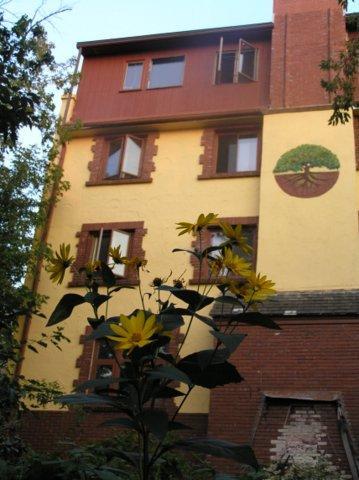 Multi-story residential building with yellow and red exterior, surrounded by greenery.