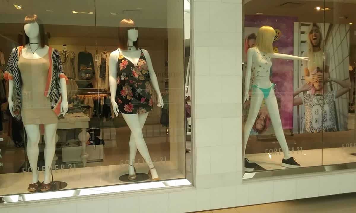 Store window display with mannequins showcasing casual summer outfits and swimwear.