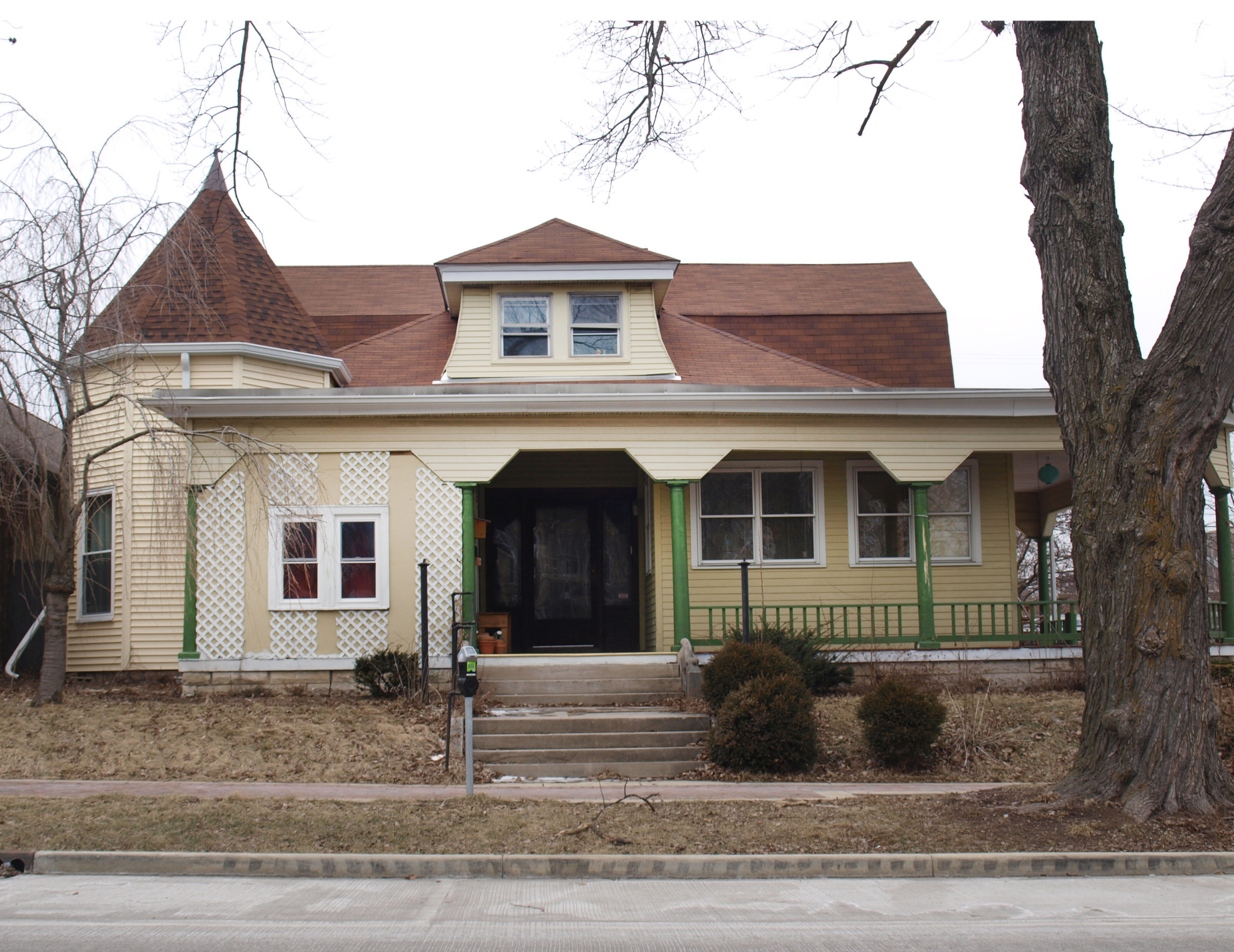 Historic house with Victorian architecture and a front porch in a residential neighborhood.