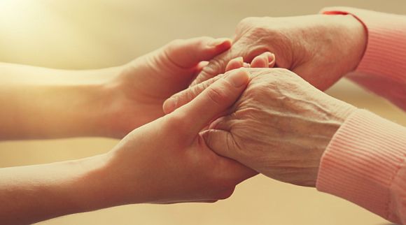 Two hands gently holding each other, symbolizing care and support.