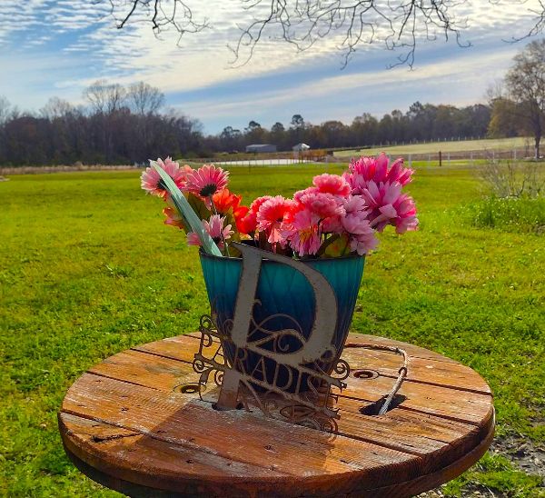 Colorful pink and red flowers in a blue vase on a wooden table outdoors.