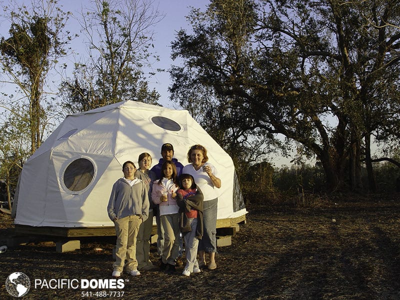 Family standing outside a geodome eco-village community.