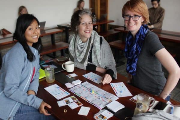 People playing cooperative social movement board game at a table.