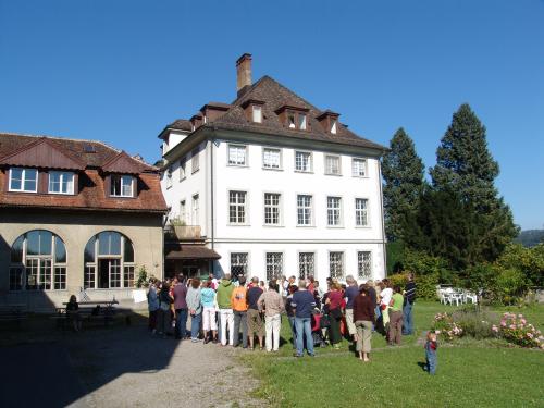 Group of people gathered outside Schloss Glarisegg in sunny weather.