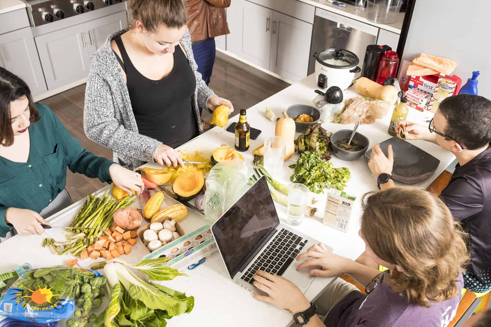 People preparing food together in a modern kitchen for community gathering.