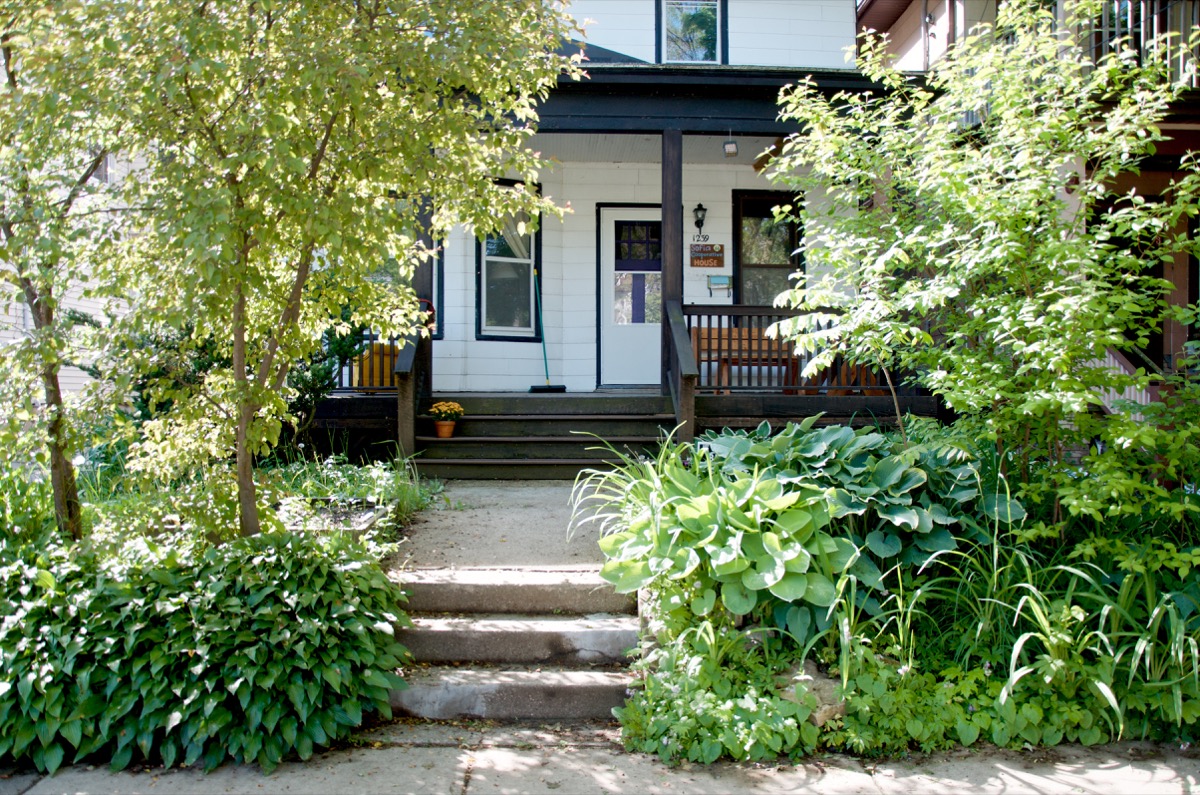 Cozy house with lush garden and wooden porch in a community setting.