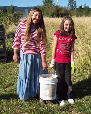 Two girls collecting honey in a field at a community farm.