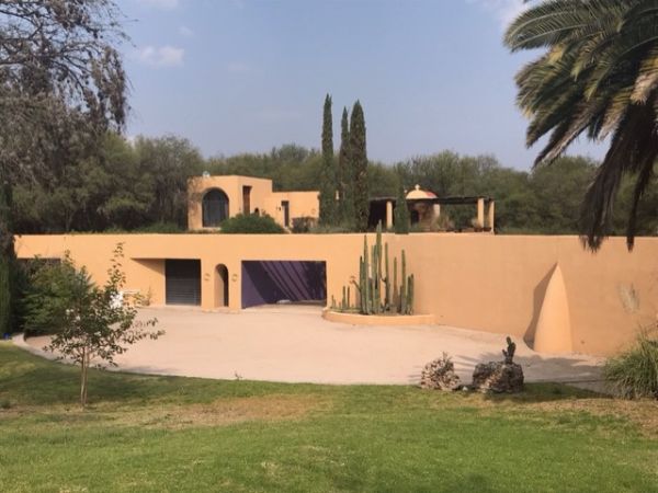 Modern adobe-style building with desert landscaping and cacti in a sunny setting.