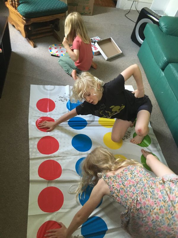 Children playing Twister game indoors at a community gathering.