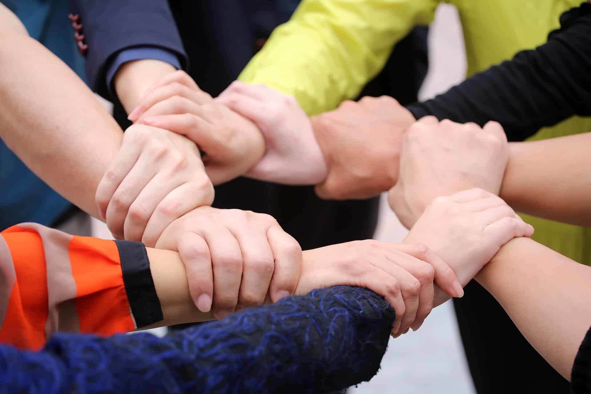 Group of diverse people holding hands in a circle for teamwork and community.