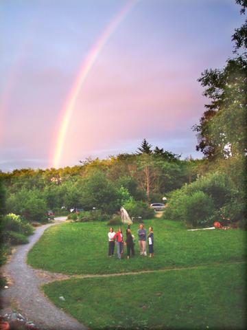 Group of people enjoying a park with rainbow and sunset sky in Vashon Cohousing.