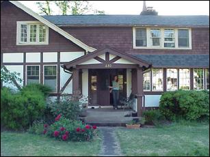 Historic community house with lush garden and welcoming porch.