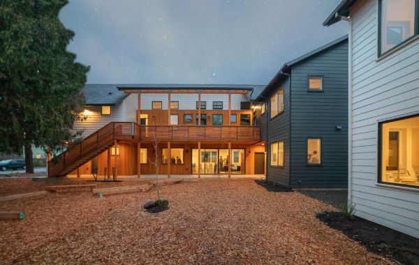 Modern community housing with wooden deck and outdoor space at night.