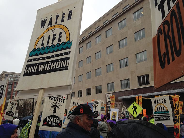 Protesters at Standing Rock holding signs against water pollution and for water protection.