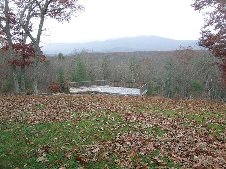 Scenic view of a forested landscape with a wooden platform and mountain backdrop.