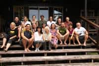 Group photo of diverse community members on wooden steps at Foundation for Intentional Community.