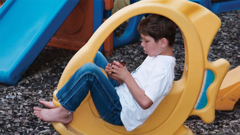 Child playing on yellow playground slide in outdoor setting.
