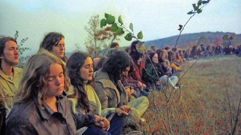 Group of people meditating outdoors in a natural setting.