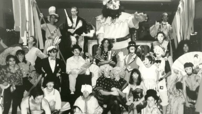 A black and white photo of a circus or carnival performance with performers in costumes.