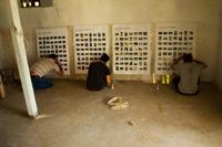 People sitting on the floor near a white lattice wall in a community space.