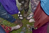 People standing in a circle on grass, holding hands, symbolizing community and connection.