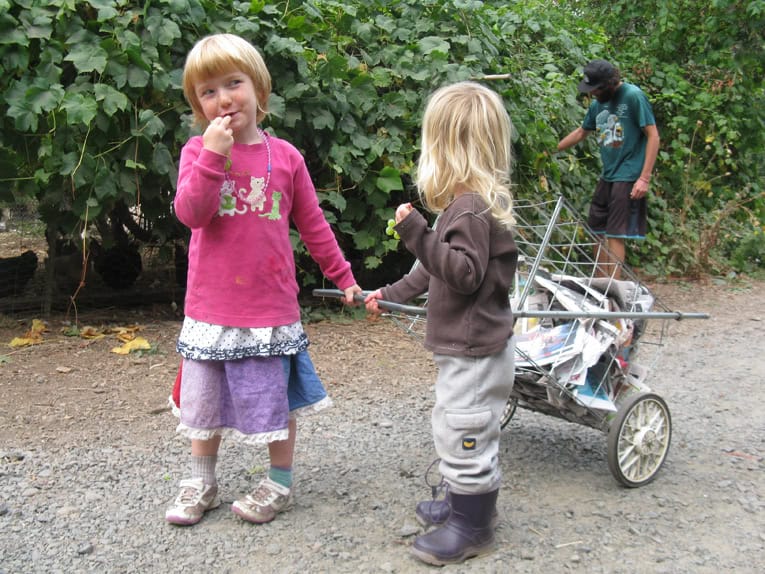 Children playing outdoors with a toy cart in a natural setting.