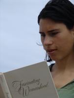 Woman reading a book about intentional community principles outdoors.
