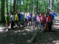 Group of people gathered outdoors in a lush green forest setting.