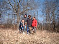 Group of people standing outdoors in a field with trees in the background.