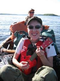 Two people enjoying a boat trip on a sunny day with a ukulele.