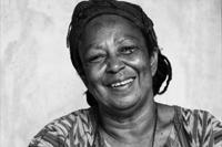 Smiling woman with braided hair in black and white photo.