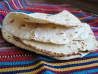 Traditional flatbread on colorful woven cloth, cultural food scene.